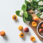 A bright still life of fresh apricots and blossoms on a cutting board, perfect for healthy eating.