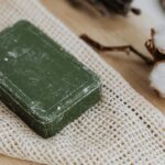 A close-up of eco-friendly green soap on natural cloth with cotton. Ideal for zero waste concepts.