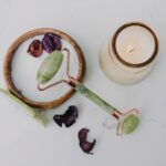 A relaxing flat lay of a jade roller and candle, perfect for a spa day at home.