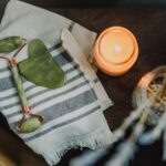 A serene spa setup featuring a jade roller, gua sha, towel, and candle for ultimate relaxation.